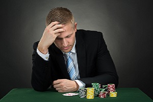 51925411 - depressed male poker with chips and cards on table