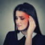 Woman holding the side of her head near her ear, illustrating symptoms associated with tinnitus and ear discomfort.