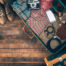Open suitcase packed with travel essentials including clothing, camera, smartphone, headphones, boots and accessories, ready for a trip.