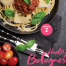 A plate of wholewheat linguine topped with minced pork Bolognese, garnished with fresh basil and parmesan shavings, served with cherry tomatoes on a dark table.