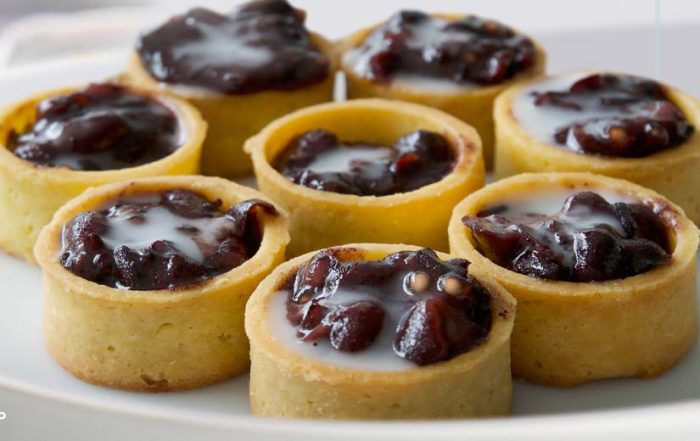 Close-up of Red Bean and Pulut Hitam Tartlets filled with sweet red bean and black glutinous rice mixture, topped with coconut milk drizzle.
