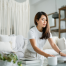 Woman practising mindful ways to declutter her room by cleaning a glass table in a calm, minimalist living space.