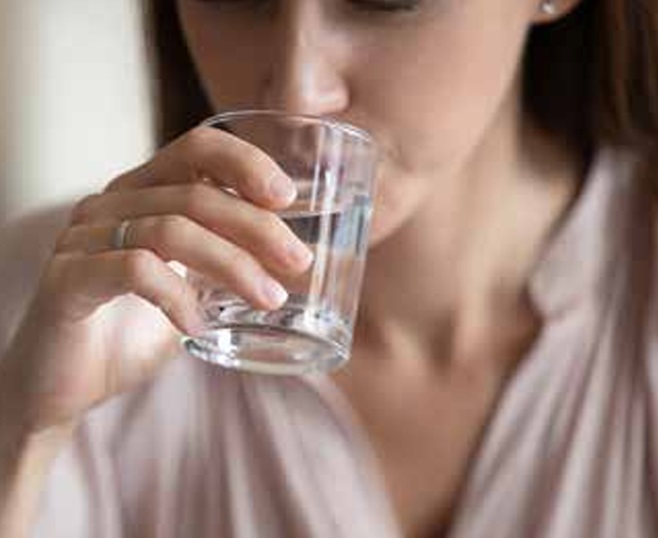 A woman drinking a glass of water, looking refreshed and hydrated