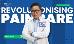 Dr Bernard Lee wearing a white coat with a name tag that reads 'Dr Pain', standing in front of a background that says 'Revolutionising Paincare
