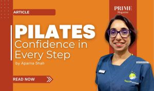 Aparna Shah, a smiling woman with short brown hair and purple glasses, wearing navy medical scrubs with the Rapid Physiocare logo, stands against an orange background. Text reads: “PILATES Confidence in Every Step by Aparna Shah,” with a red “Read Now” button and the PRIME Magazine logo.