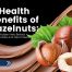 Close-up of hazelnuts with green leaves and smooth chocolate background, overlaid with the text “Health Benefits of Hazelnuts: The Hidden Hero Behind Chocolate and Heart Health.”