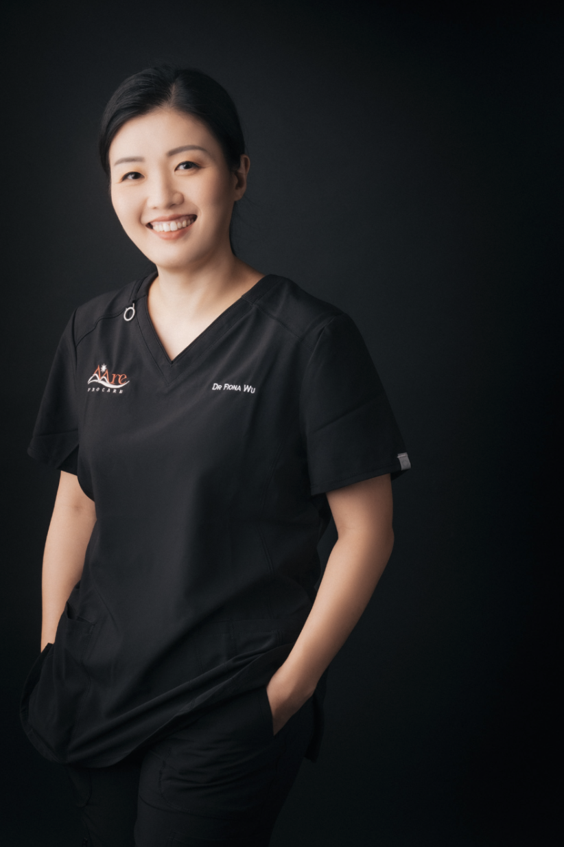 Dr Fiona Wu smiling in black AARE Urocare medical scrubs against a dark background.
