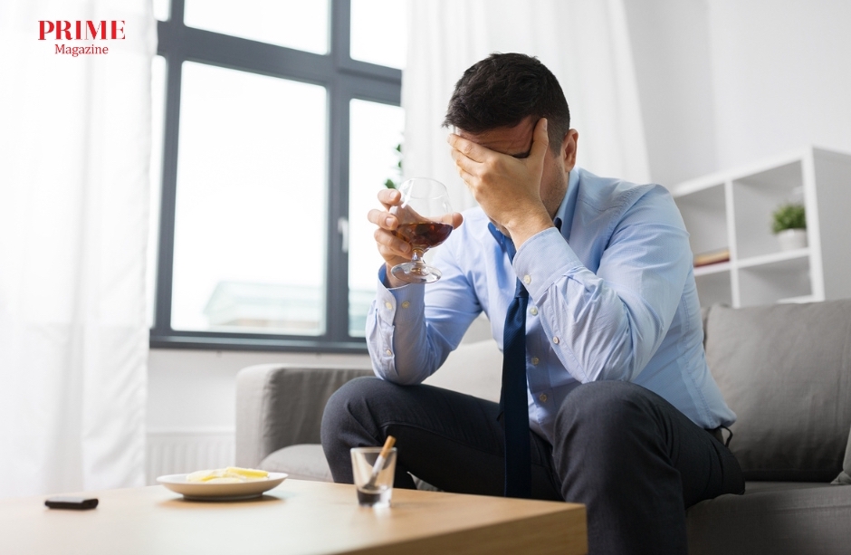 Man looking stressed while drinking alcohol at home, representing alcohol-related stress and health risks.