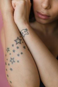 Small star and minimalist tattoos on a woman’s forearm.