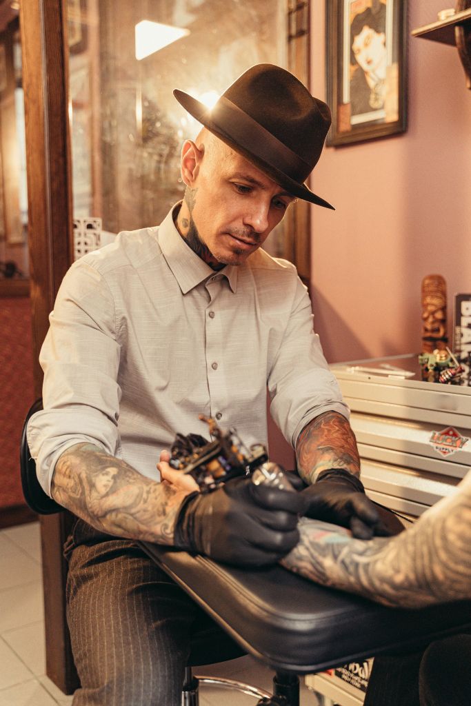 Professional tattoo artist creating a sleeve tattoo in a studio, illustrating the craftsmanship behind modern tattoo culture.