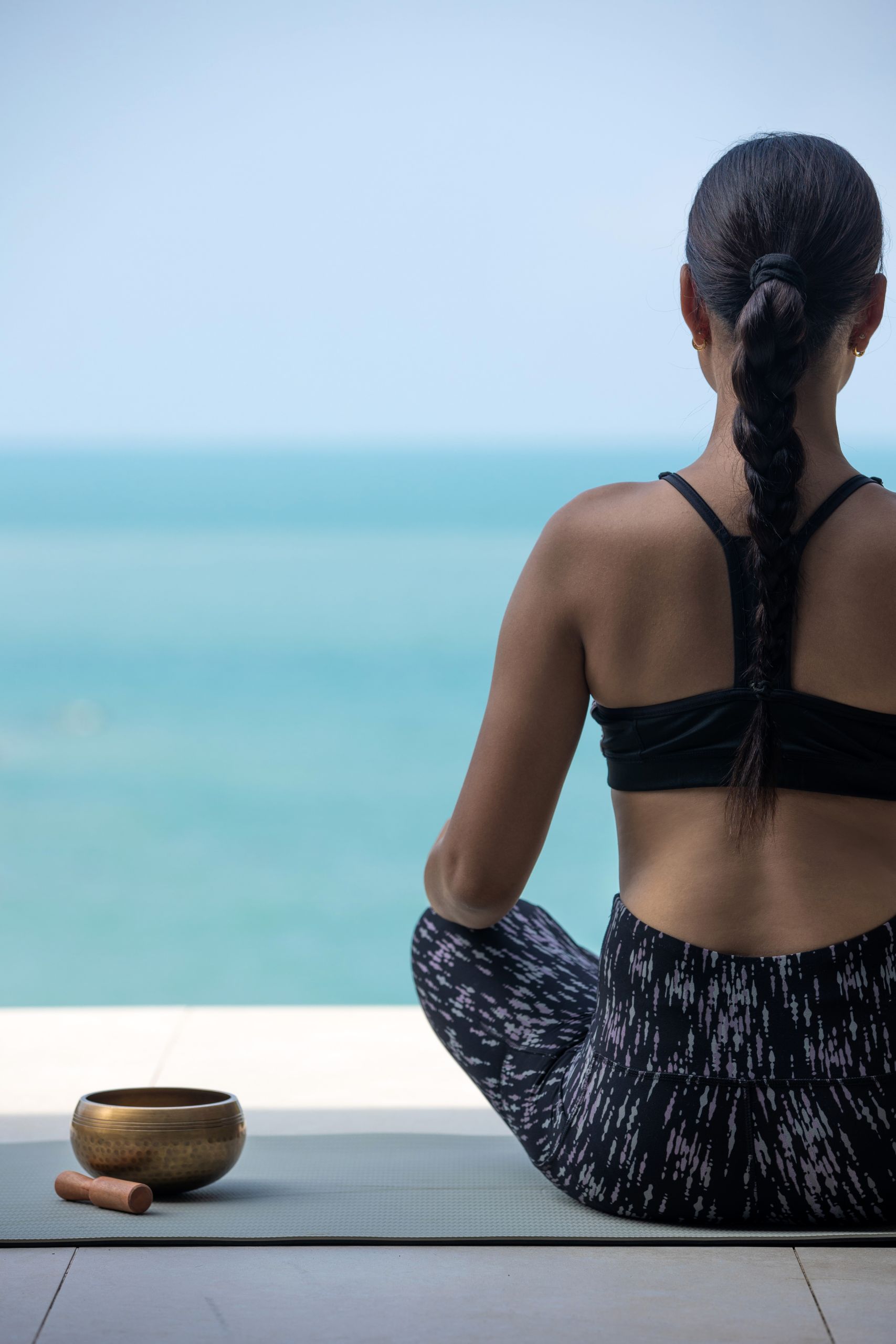 A guest practices mindfulness meditation overlooking the ocean at Garrya Tongsai Bay Samui in Koh Samui, Thailand.