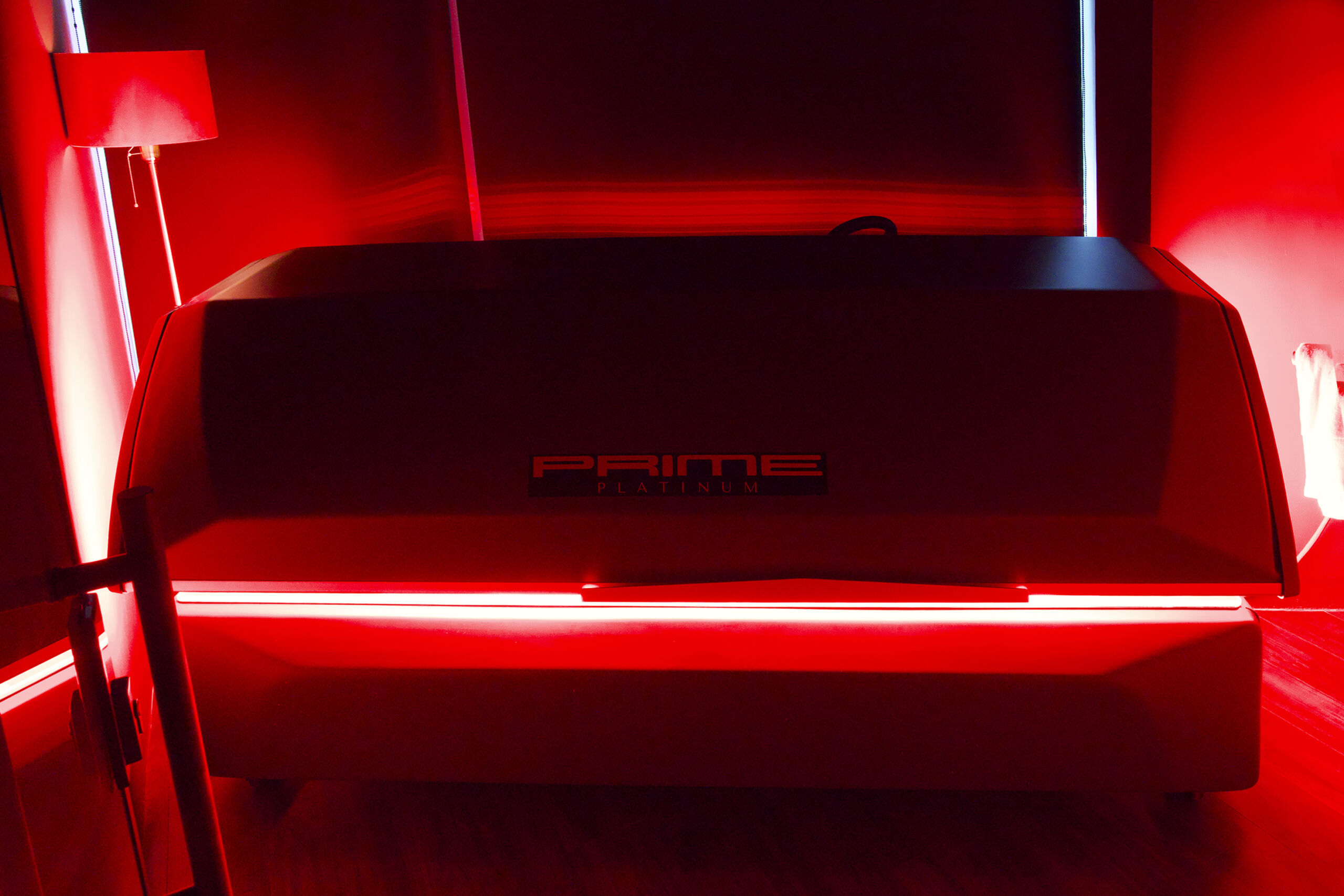 Full-body red light therapy bed at RAPIDÉ Recovery Atelier, illuminated by red lights.